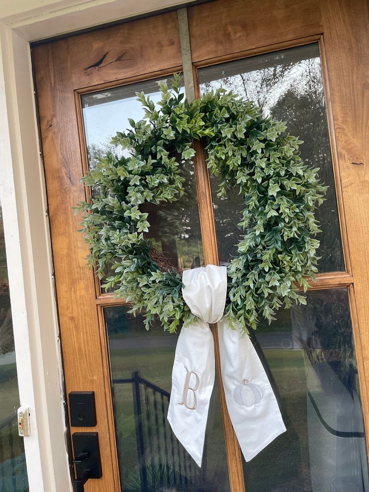 a wreath on the front door of a house that has been decorated with white ribbon