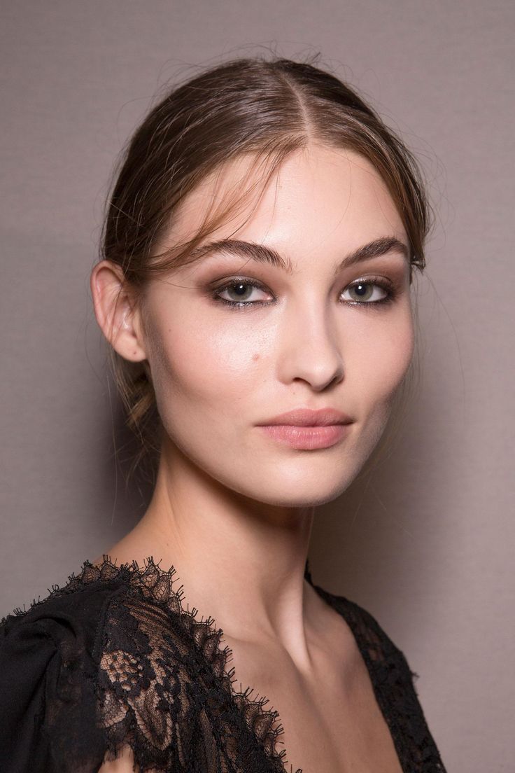 a woman with long hair and smoky eyeshadow wearing a black lace dress, posing for the camera