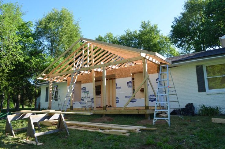 a house being built in the middle of a yard with wood framing on the roof