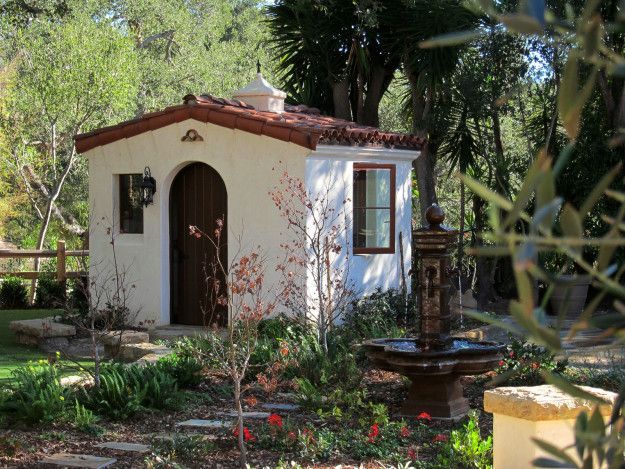 a small white house with a fountain in the front yard