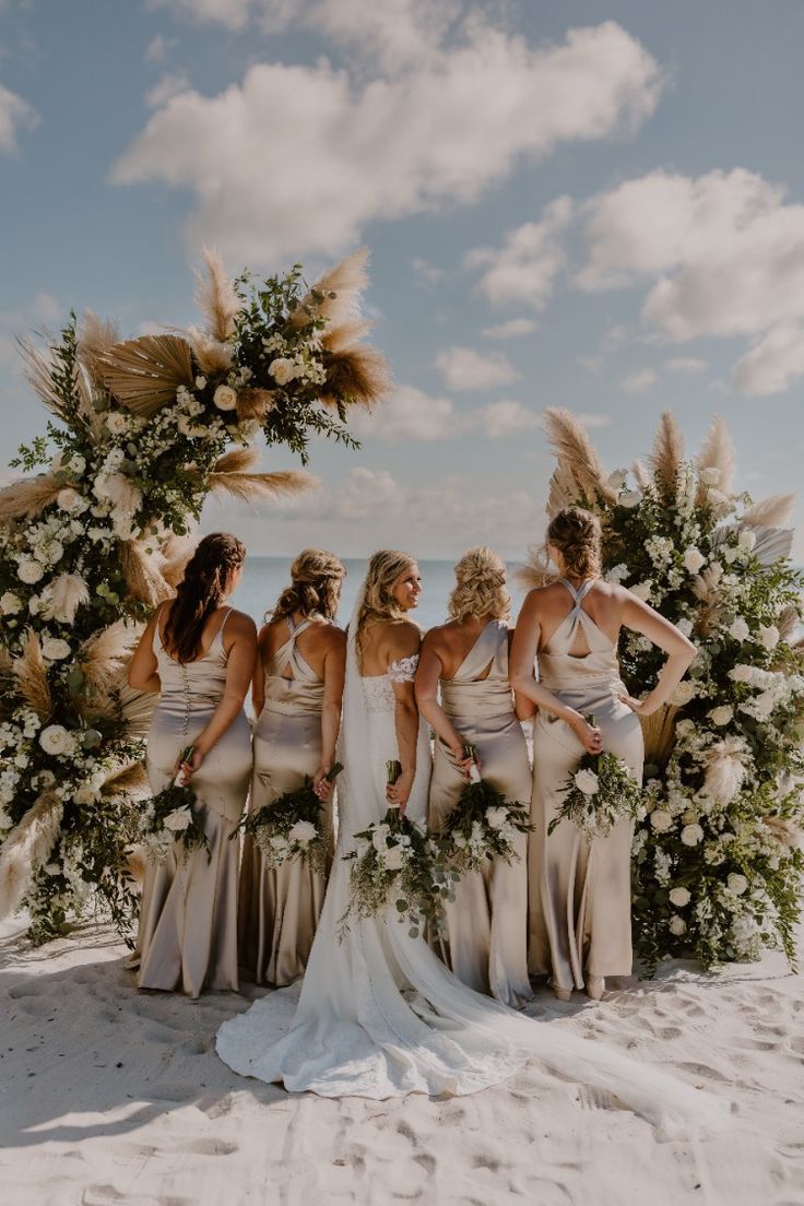 a group of women standing next to each other on top of a sandy beach covered in flowers