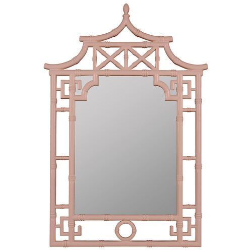 a mirror that is sitting on top of a table with a light pink frame around it