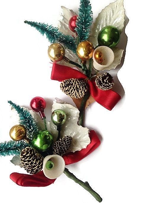 two christmas decorations with pine cones, ornaments and bells on them are sitting next to each other