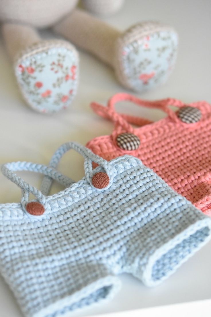 three crocheted purses sitting on top of a table next to a teddy bear