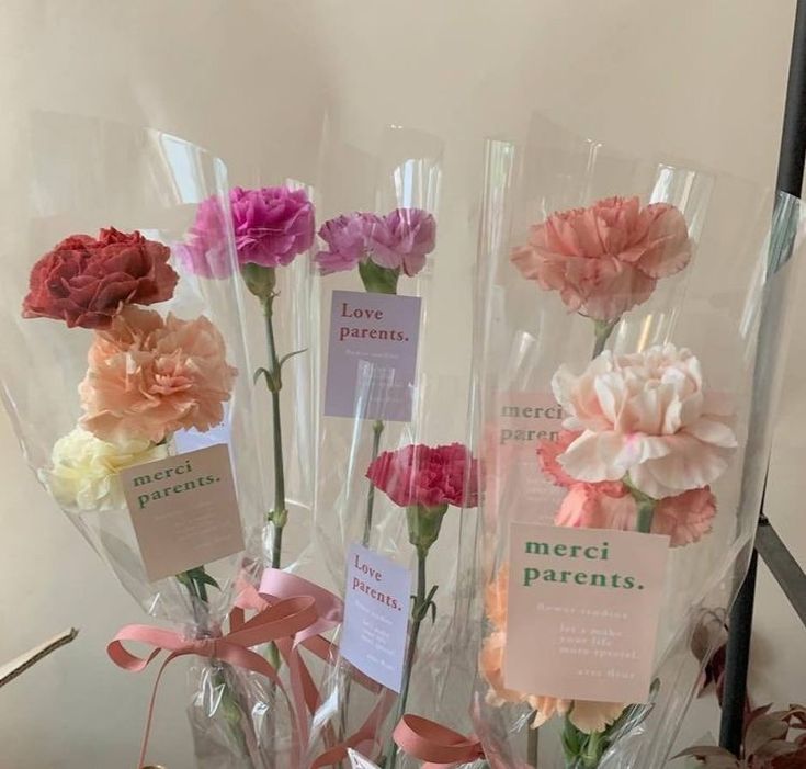 three clear vases with flowers in them and labels on the stems that say love