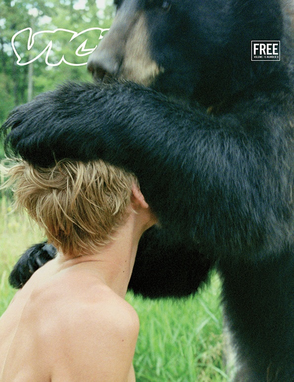 a young man is touching a large black bear