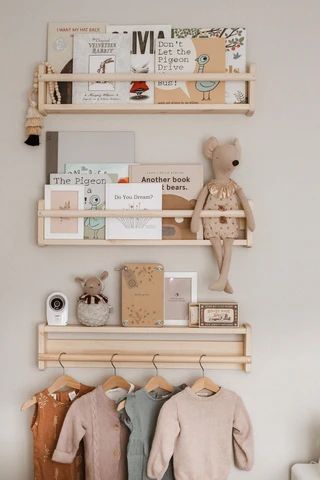 two wooden shelves with clothes hanging on them and a teddy bear in the corner next to it