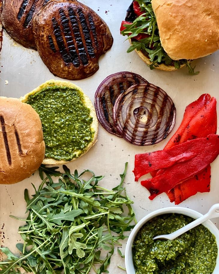 an assortment of burgers with pesto sauce on them and other toppings next to each other