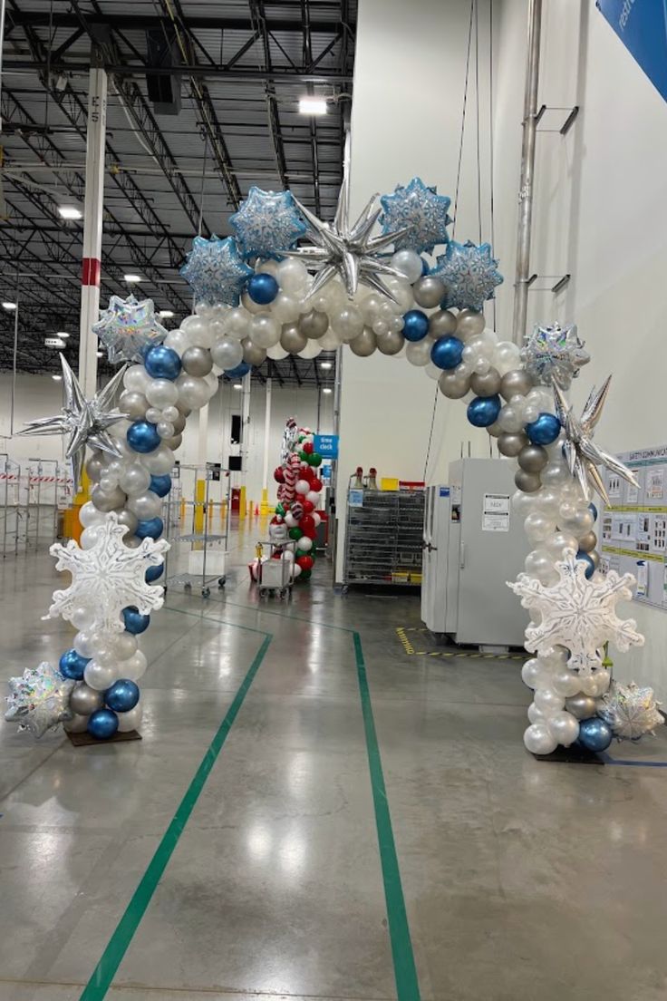 an arch made out of balloons and snowflakes is displayed in the middle of a building