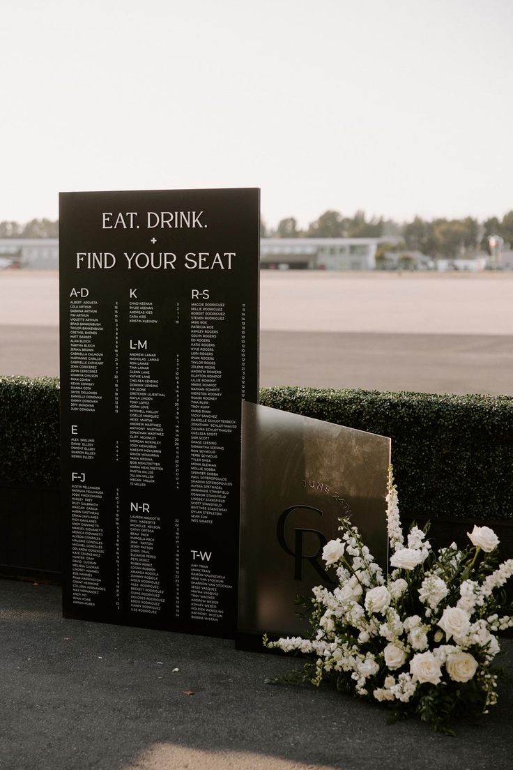 a table with flowers on it next to a sign that says eat drink find your seat