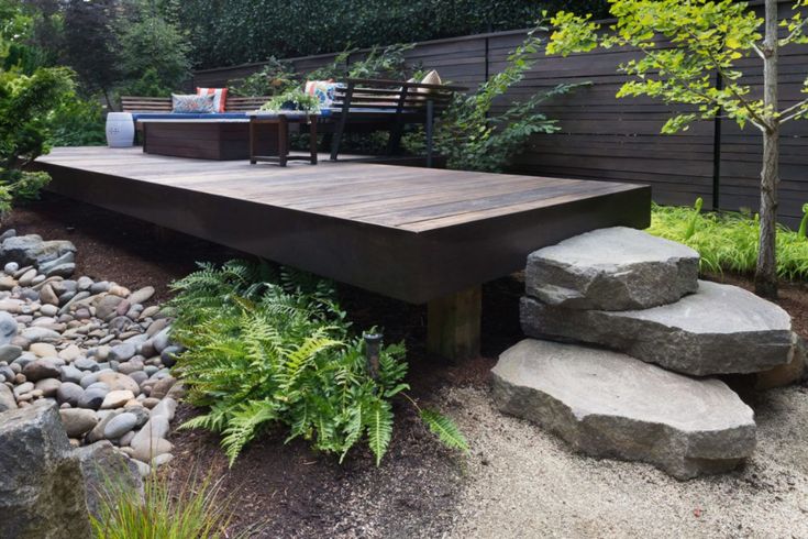 a wooden deck surrounded by rocks and plants