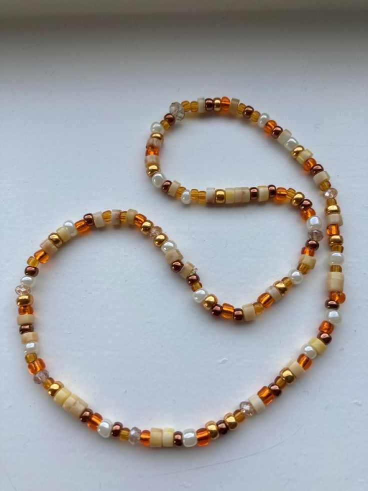 a beaded necklace is shown on a white surface with an orange and yellow bead