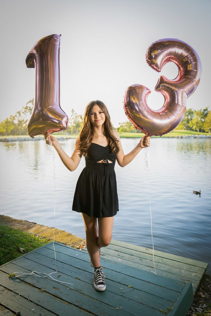 a young woman holding two large balloons in front of her face and the number thirteen