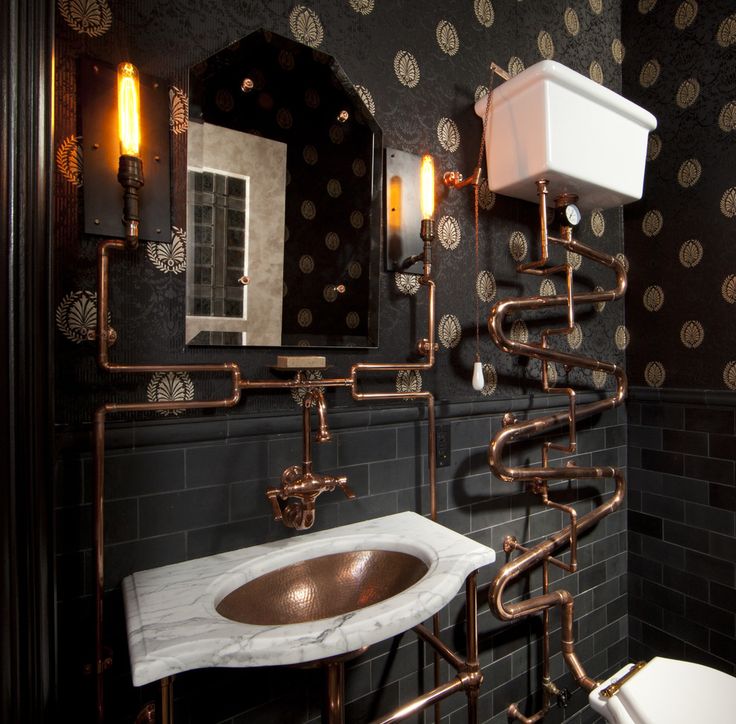 a bathroom with black and gold wallpaper, copper pipes, white sink and toilet