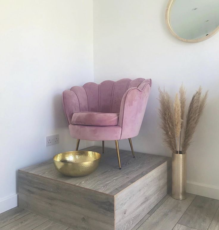 a purple chair sitting on top of a wooden platform next to a gold bowl and mirror