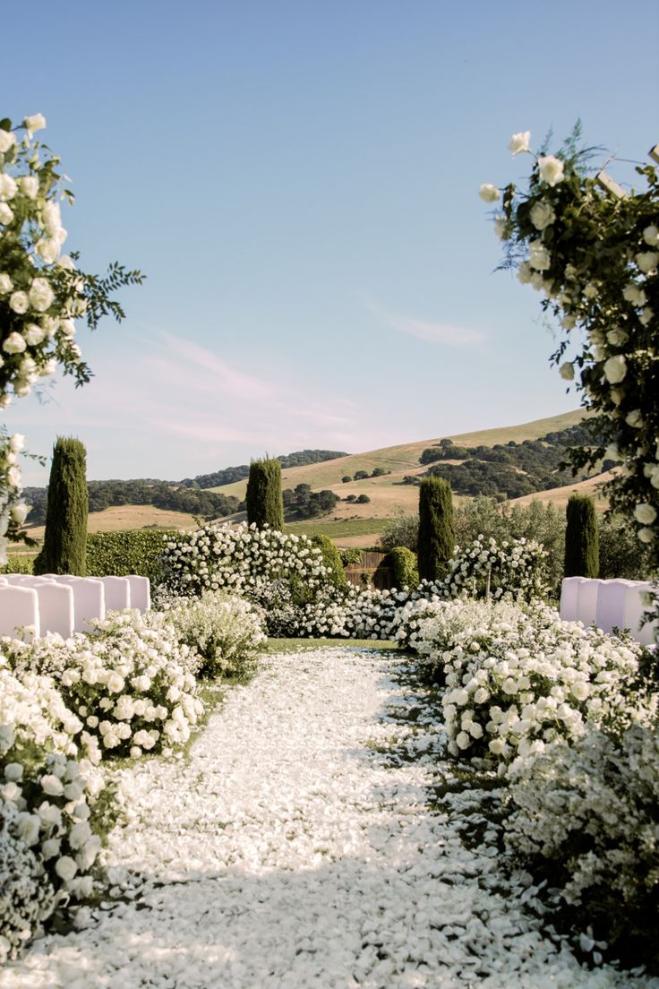 an outdoor ceremony with white flowers and greenery