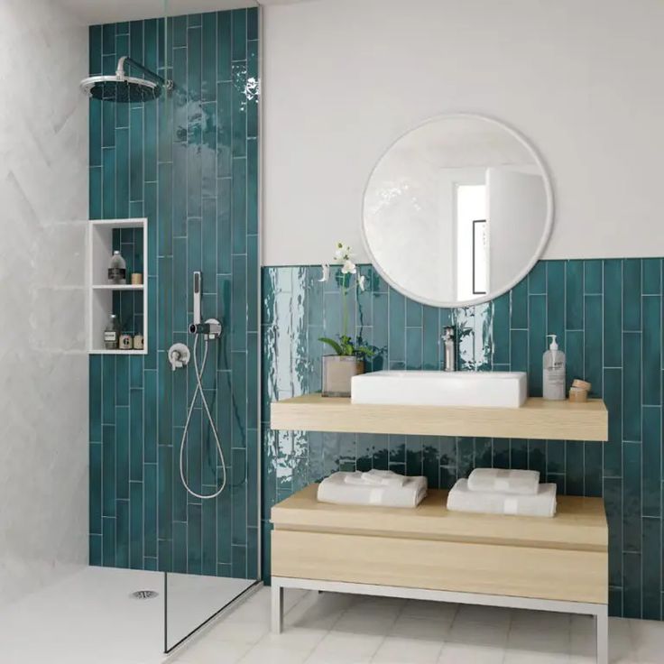 a bathroom with blue tiles and white fixtures, including a shower head mounted on the wall