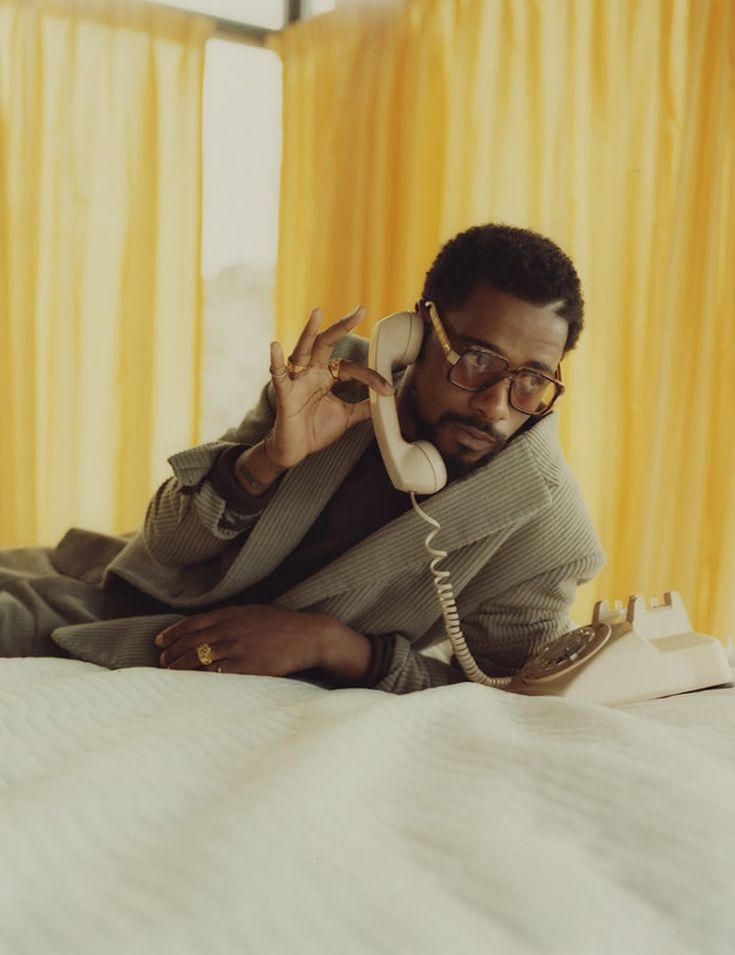 a man laying on top of a bed talking on a phone