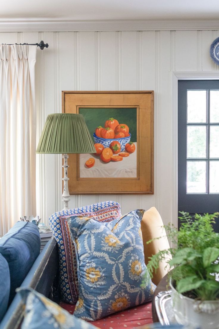 a living room filled with furniture and a painting hanging on the wall above it's windows