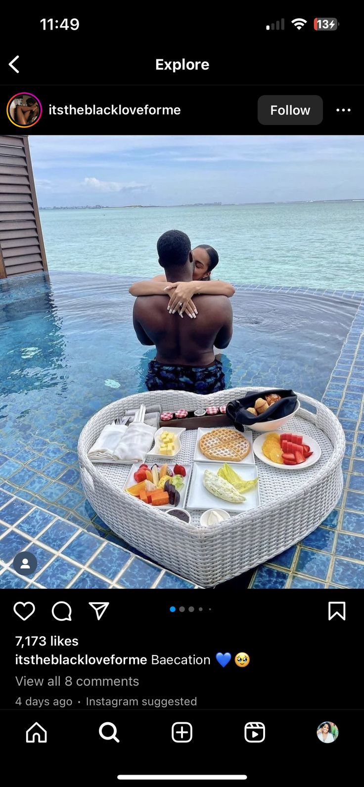 two people sitting on a table with food in the middle of it and one person taking a selfie