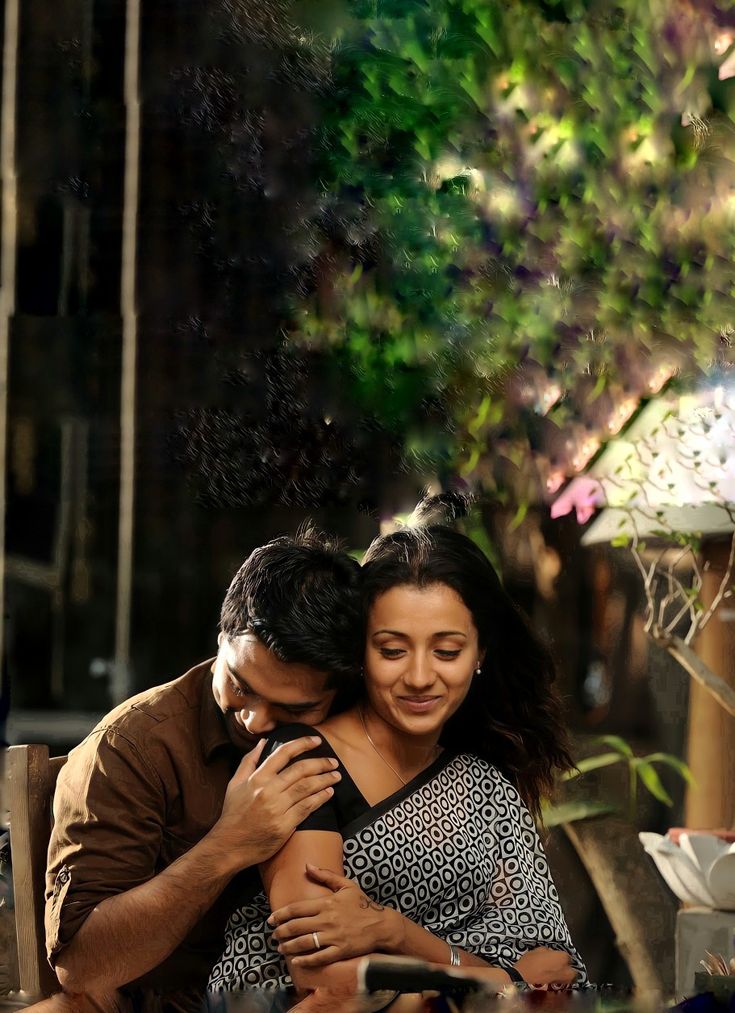 a man and woman hugging each other while sitting at a table with food in front of them