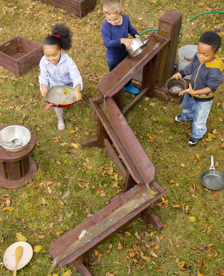 three children are playing in the yard with pots and pans