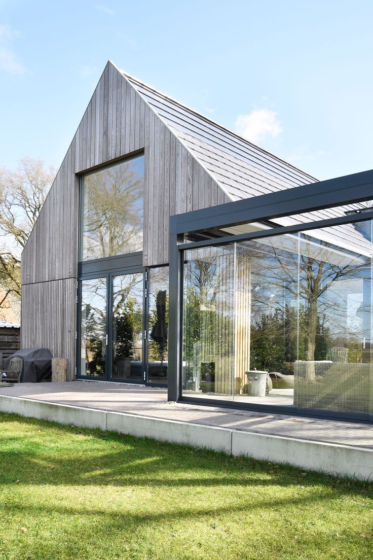 a modern house with glass walls and sliding doors on the outside, grass in front