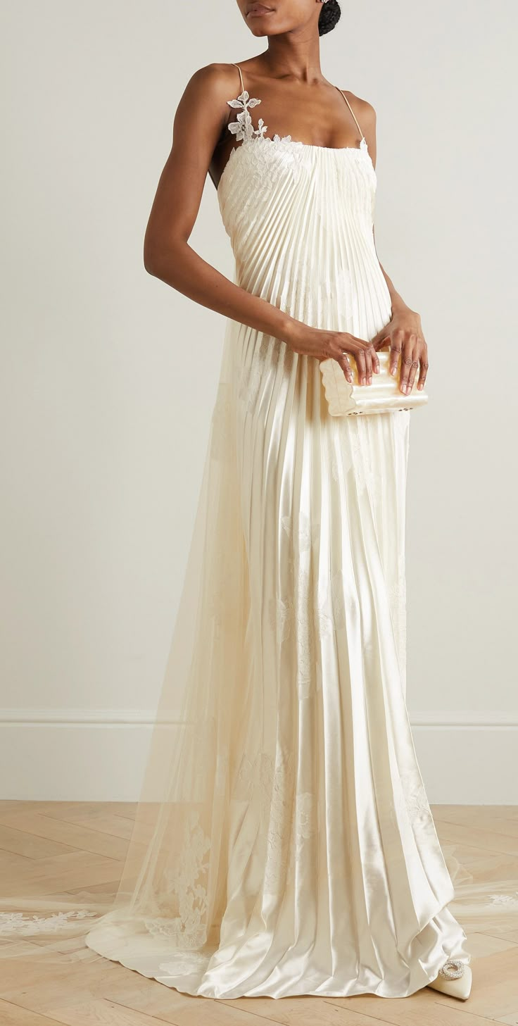 a woman in a white dress standing on a wooden floor holding a purse and looking off to the side