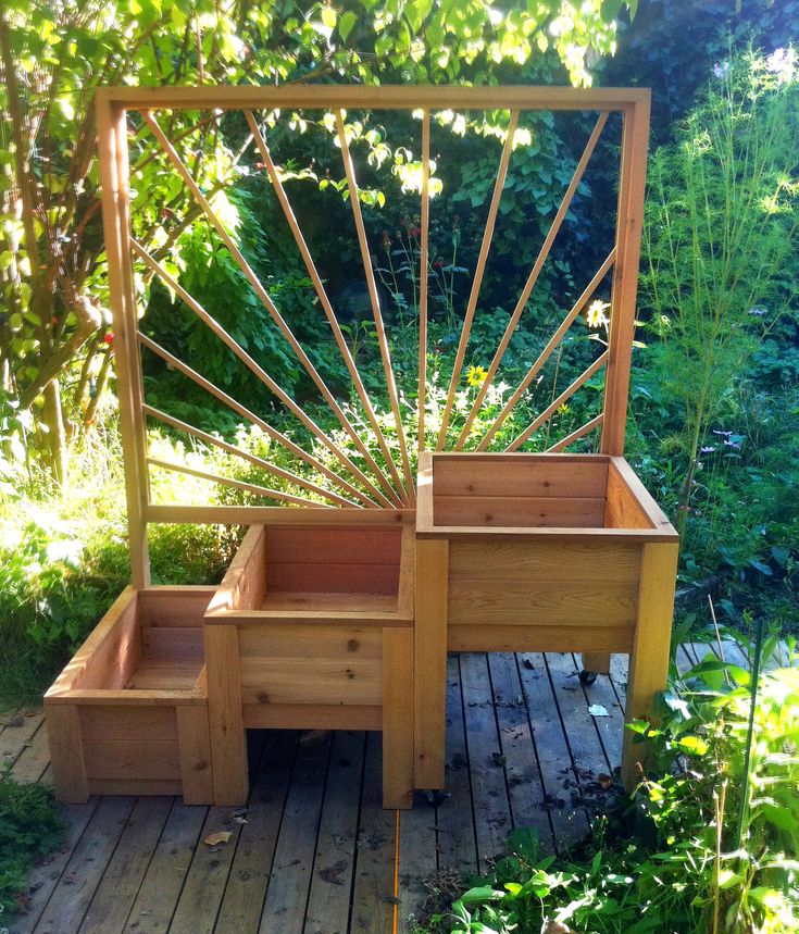 a wooden deck with planters and steps in the middle, surrounded by greenery