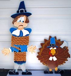 two turkeys and a scarecrow standing next to each other in front of a garage door