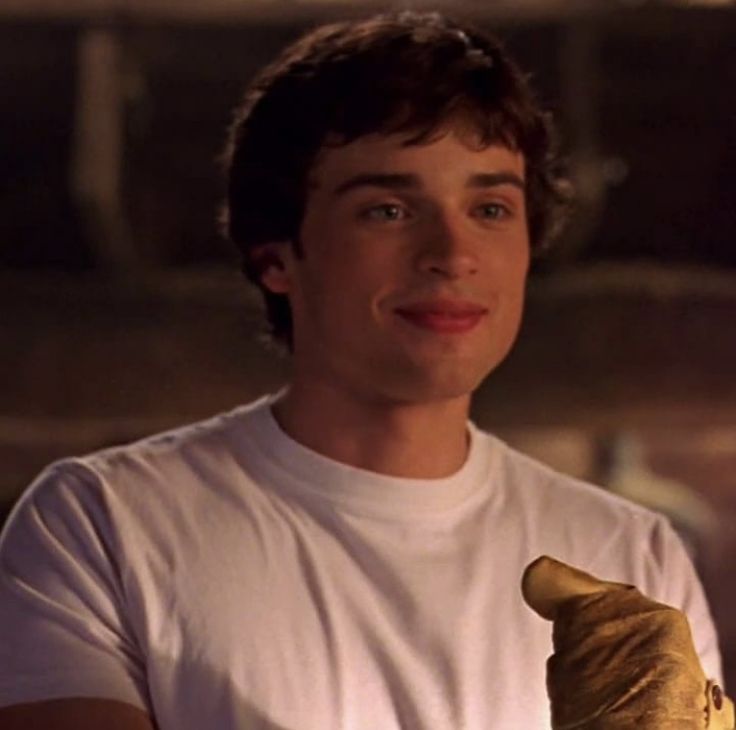 a young man holding a banana in his right hand and looking at the camera while wearing a white t - shirt