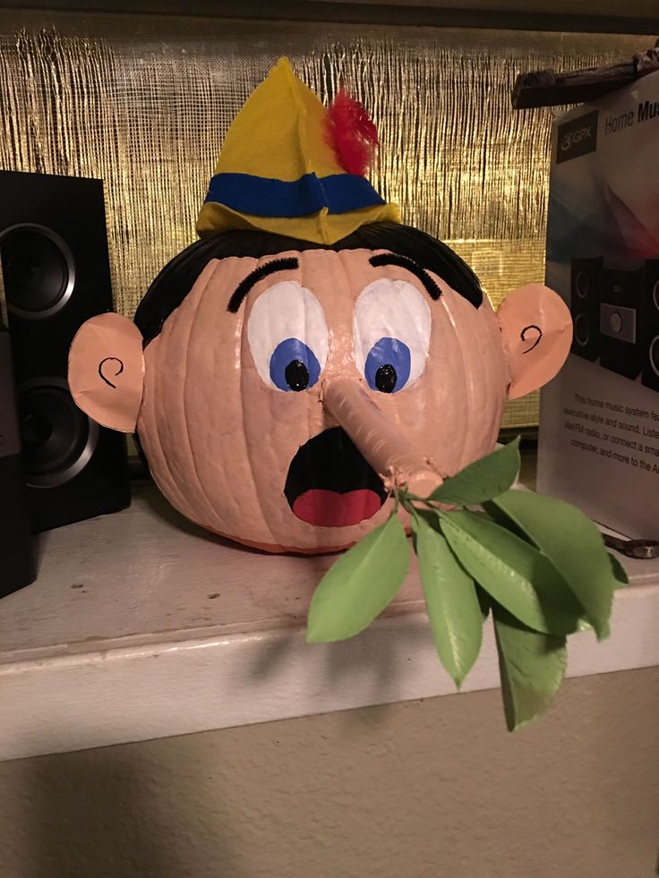 a pumpkin with a face painted on it sitting on top of a shelf next to speakers