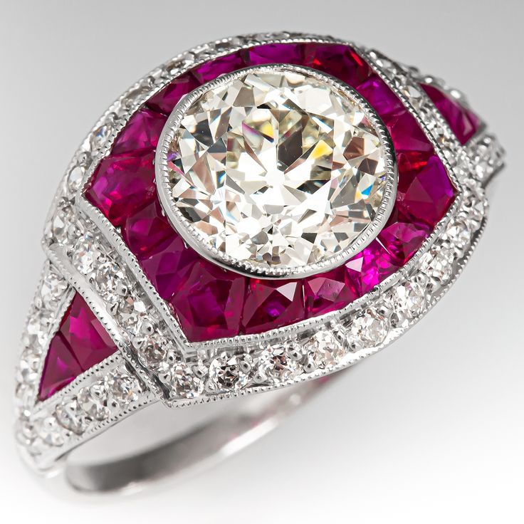 This striking Art Deco style ring is centered with one (1), bezel set, old European cut diamond and bordered with sixteen (16), channel set, calibre' cut natural rubies and twenty-six (26), bead set, old European cut diamonds. The shoulders of the ring are ach accented with two (2), channel set, calibre' cut natural rubies and nine (9), bead set, old European cut diamonds. The gemstones are bordered with milgrain edging. The ring measures 13.6mm at the top, rises 5.2mm above the finger, tapering Athena Jewelry, Victorian Princess, Antique Cocktail Ring, Angel Princess, Rings Antique, Diamond Jewelry Designs, Rings Fashion, Bead Set, Antique Engagement Rings