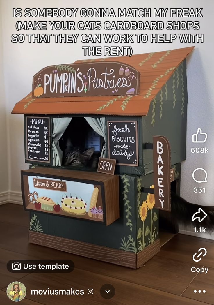 a dog house made out of cardboard and painted with pumpkins on the outside, in front of a white wall