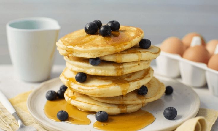 a stack of pancakes with blueberries and syrup