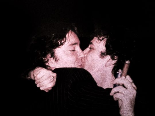 two men are kissing each other in the dark