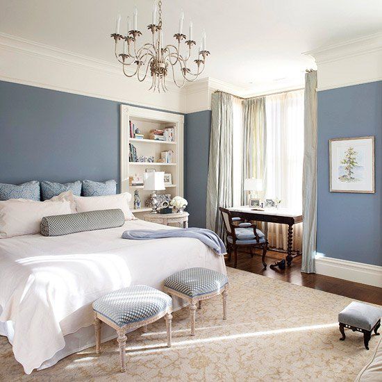 a bedroom with blue walls and white bedding, chandelier hanging from the ceiling