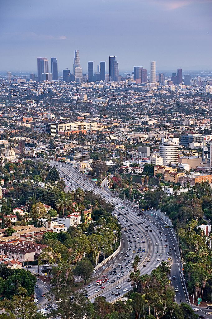 an aerial view of a city and freeway with tall buildings in the backround