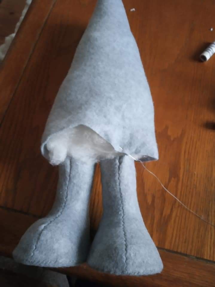 a white stuffed animal sitting on top of a wooden table next to scissors and thread