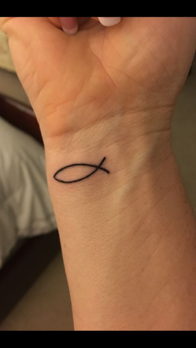 a woman's wrist with a small fish tattoo on the left side of her arm