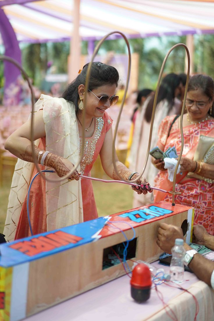 a woman in a sari is making something out of cardboard with scissors and wires