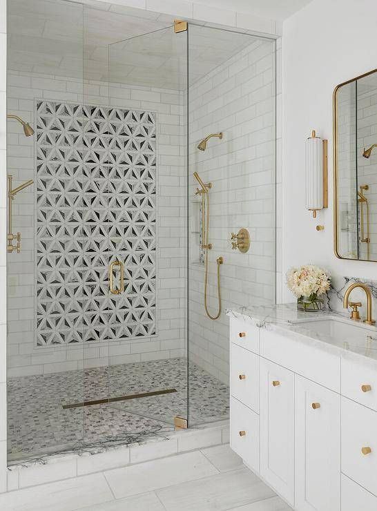 a white bathroom with gold accents and marble counter tops, along with a walk in shower