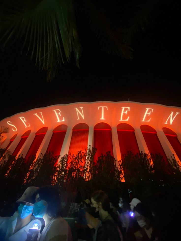 people are standing in front of the neon sign that says,'s seventeen