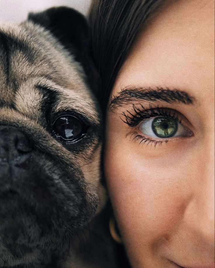 a close up of a person with a pug on their shoulder and the dog's face next to her