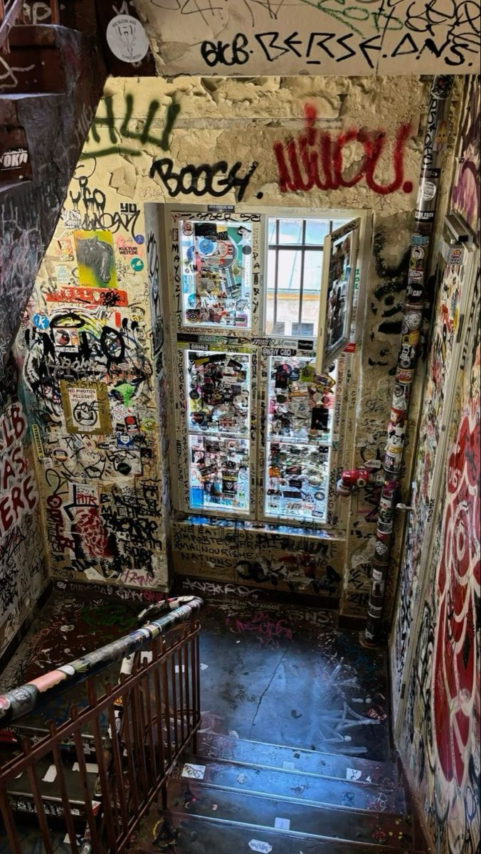 an alleyway with graffiti all over the walls and stairs leading up to a window