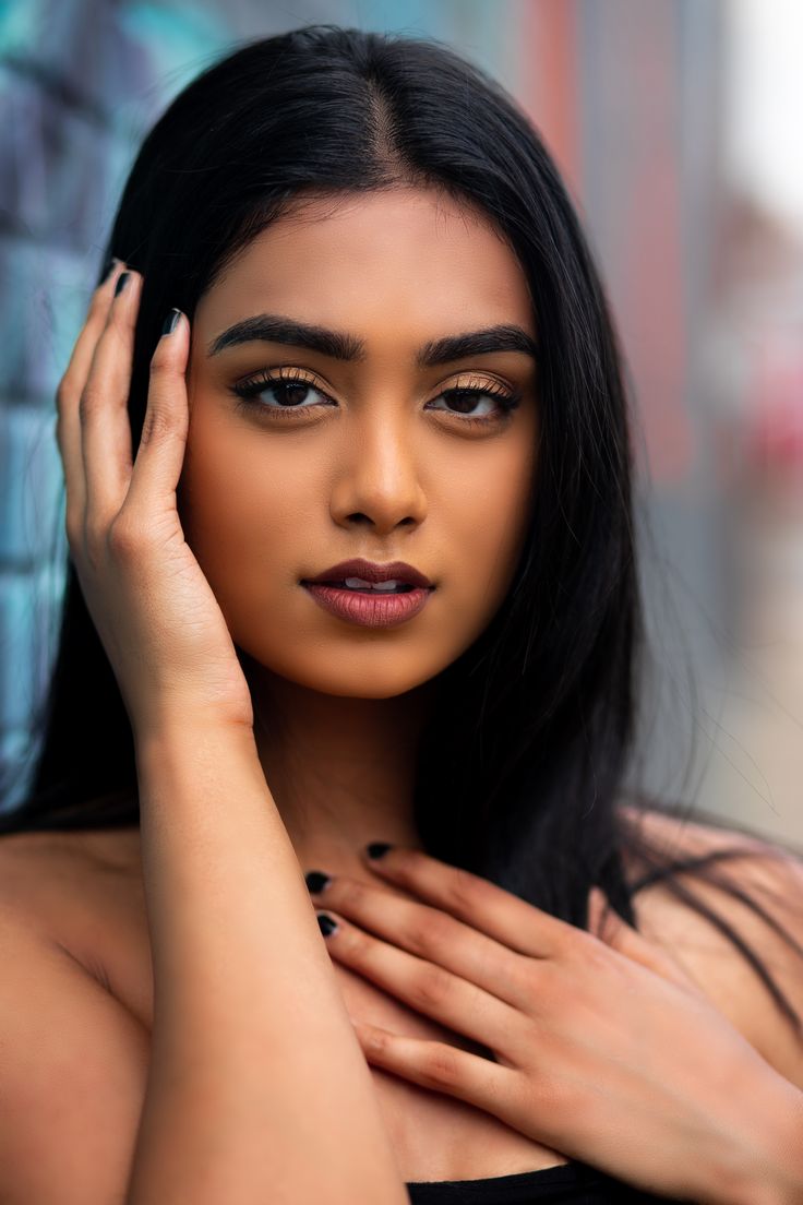 a woman with long black hair posing for the camera