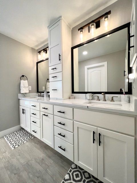 a large bathroom with white cabinets and black trim on the mirror over the sink, along with an area rug