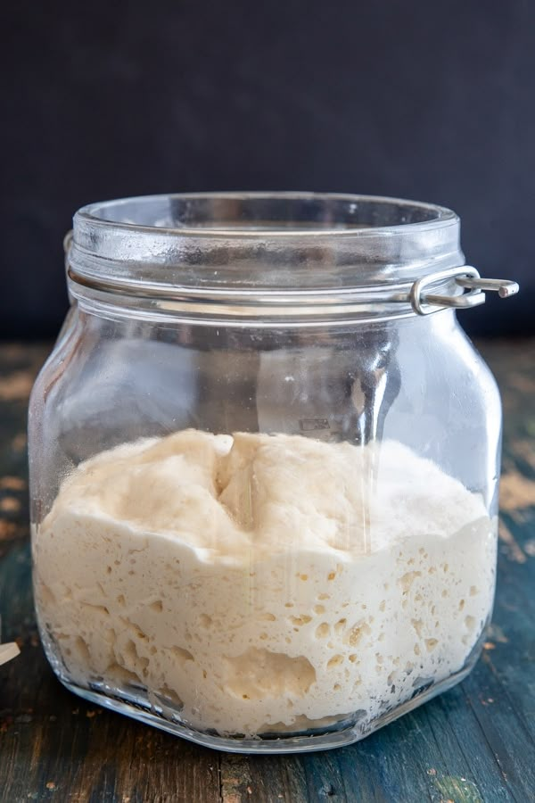 a glass jar filled with food sitting on top of a wooden table next to a spoon