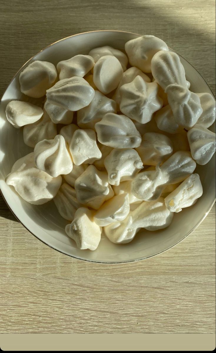 a white bowl filled with marshmallows on top of a wooden table