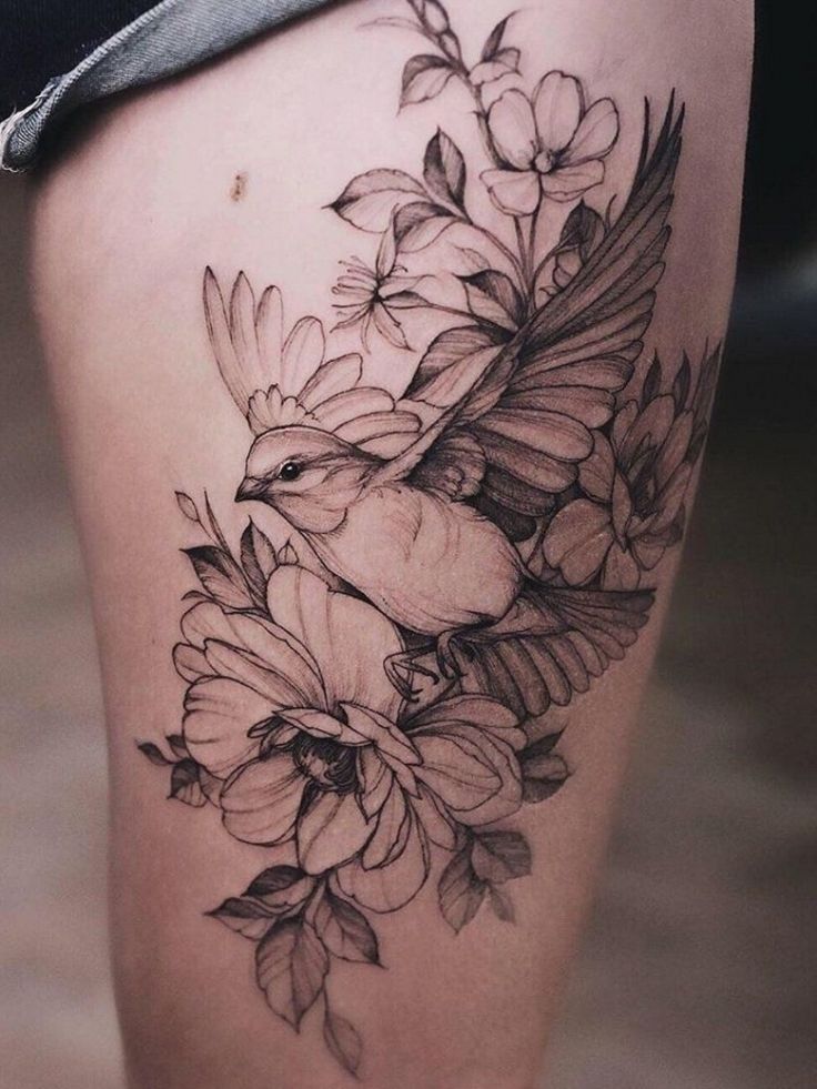 a woman's thigh with flowers and bird tattoo on the side of her leg